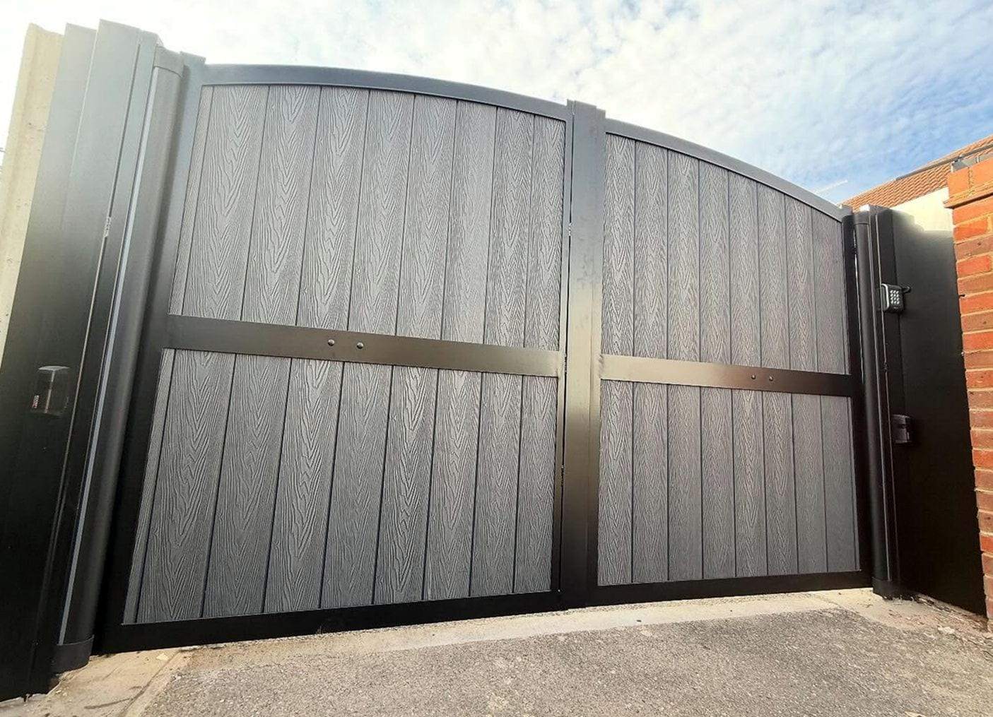Gray wood-grain composite double gate in a black frame with an access keypad on the right-hand post
